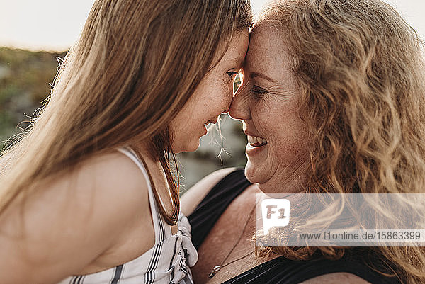Side view of mother and redheaded elementary age daughter at sunset