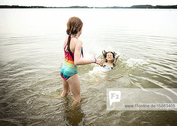 Zwei junge Mädchen im Badeanzug spielen in einem See