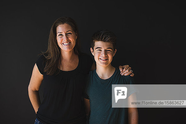 Porträt eines Teenagers und seiner Mutter vor einem dunklen Hintergrund.