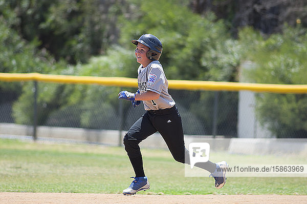 Little League baseball player running the bases with a big smile