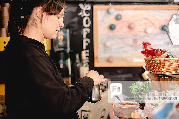 Weiblicher Barista  der im Café stehend Kaffee zubereitet