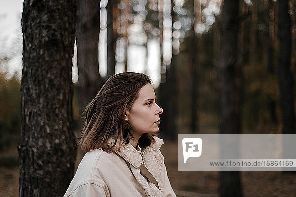 Portrait of young woman on trees background at forest