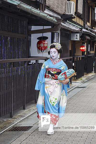 Maiko  Geisha-Lehrling  geht zur abendlichen Verabredung vorbei an traditionellen Teehäusern aus Holz  Gion  Kyoto  Japan  Asien