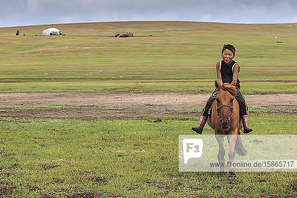 Pferd und Junge reiten ohne Sattel mit Ger dahinter im Sommernomadenlager  Khujirt  Uvurkhangai (Ovorkhangai)  Zentralmongolei  Zentralasien  Asien