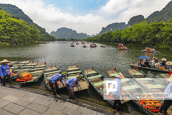 Boats with lifejackets and tour guides standing at the water's edge of the Red River  Red River Delta; Ninh Binh  Ninh Binh  Vietnam