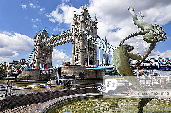 Tower Bridge on the River Thames and The Shard in the background with a fountain and tourists in the foreground; London England