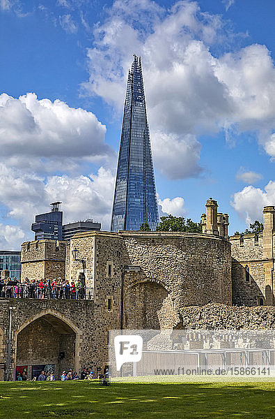 Tourists at the Tower of London with the Shard commerical skyscraper in the background; London England