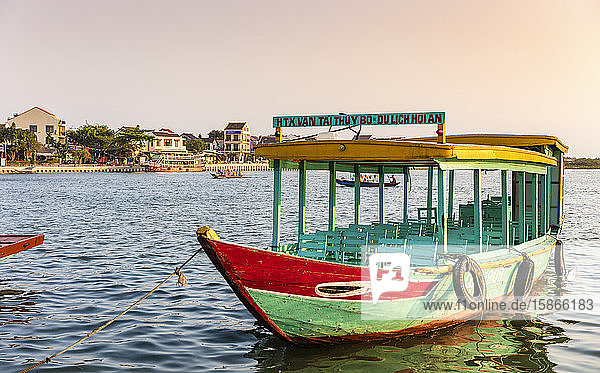 Colourful tour boat moored in the water along the waterfront at sunrise; Hoi An Quang Nam Province Vietnam
