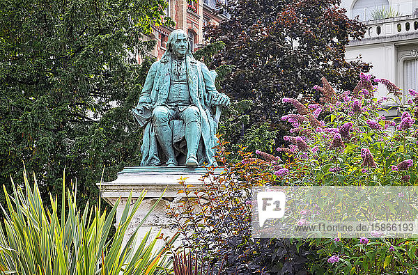 Benjamin Franklin statue in a garden with trees and blossoming plants; Paris France