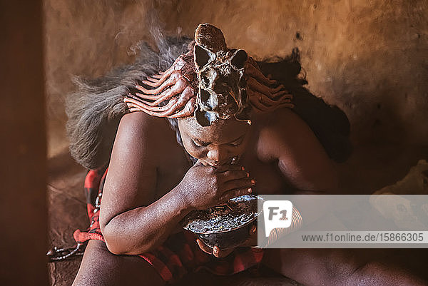 Himba woman preparing incense to wash her hair with the smoke Himba village; Kamanjab Namibia