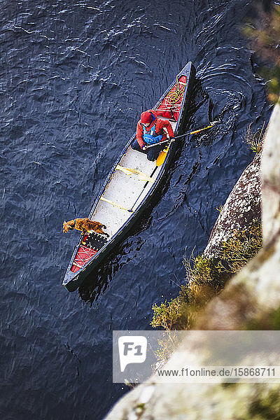 High angle view of woman and dog paddling a canoe on a lake in Ireland in winter  Killarney National Park; County Kerry  Ireland