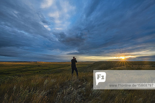 Person taking a photo of the sunrise in Grasslands National Park; Saskatchewan Canada