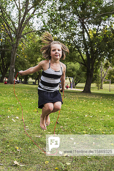 A young girl skipping with a skipping rope in a park; Edmonton  Alberta  Canada