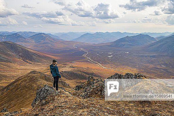 Frau erkundet die Berge entlang des Dempster Highway im Herbst; Yukon  Kanada