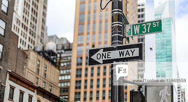 Straßenschilder an einem Pfosten  eine Einbahnstraße  Fußgängersignal und West 37th Street  Manhattan; New York City  New York  Vereinigte Staaten von Amerika