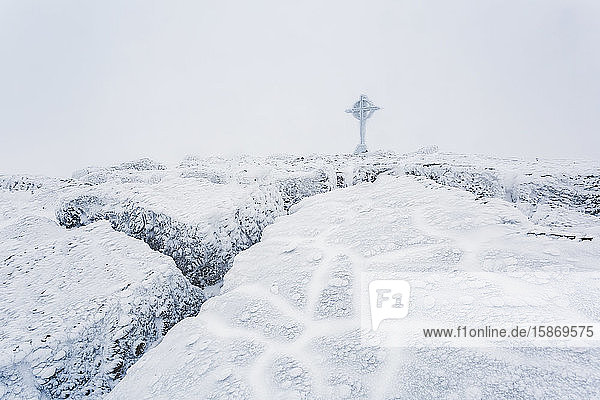 Gefrorene Eisformationen auf dem Gipfel des Berges Galtymor mit einem keltischen Kreuz im Winter  Galty Mountains; County Tipperary  Irland