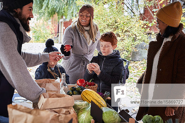 Lächelnde Frau kauft am Gemüsestand frische Äpfel von männlichem Marktverkäufer