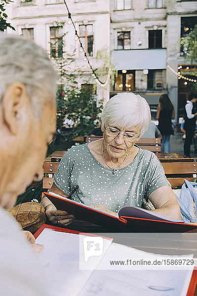 Älterer Mann und Frau lesen die Speisekarte  während sie in einem Restaurant in der Stadt sitzen