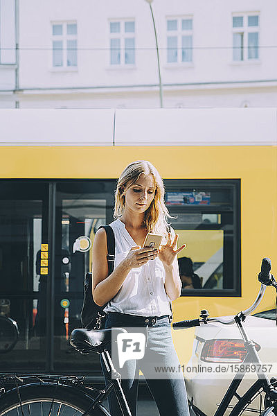 Geschäftsfrau benutzt Smartphone  während sie in der Stadt mit dem Fahrrad steht