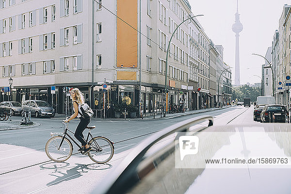 weibliche Führungskraft in voller Länge mit dem Fahrrad auf der Straße in der Stadt