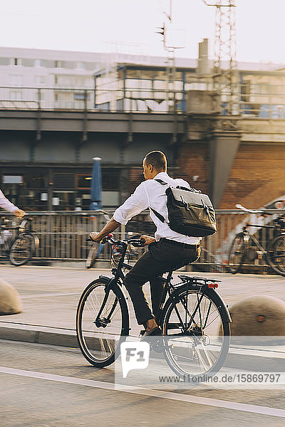 Seltener Anblick eines männlichen Exekutivbeamten beim Fahrradfahren auf einer Straße in der Stadt gegen den Himmel