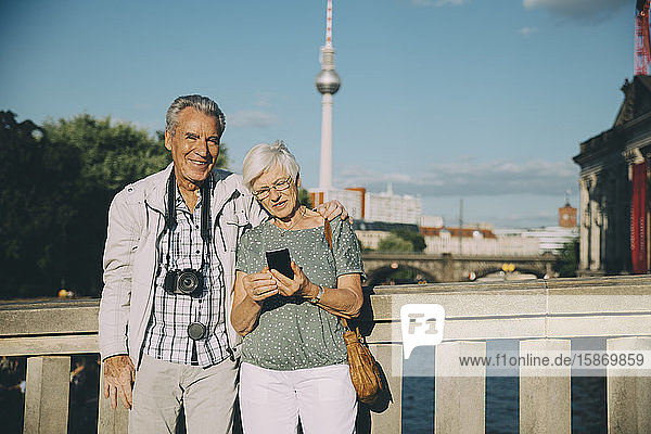 Älterer Mann Arm um Arm mit Frau auf Brücke in der Stadt stehend