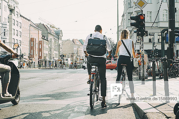 Geschäftsmitarbeiter in voller Länge stehen mit Fahrrädern am Straßenverkehrssignal in der Stadt