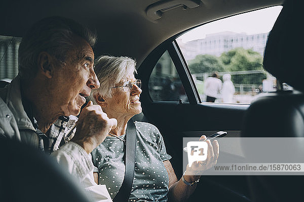 Ältere Frau hält Handy in der Hand  während sie mit Mann im Auto sitzt