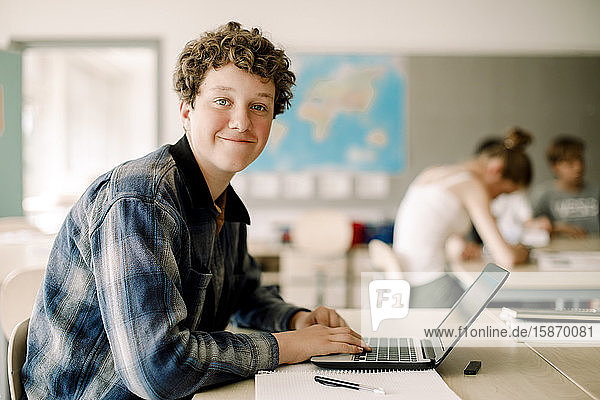Porträt eines Teenagers  der im Klassenzimmer am Laptop sitzt