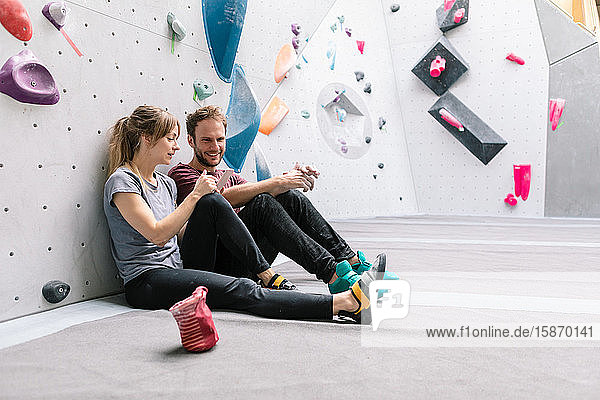 Female showing mobile phone to smiling male friend while sitting in gym