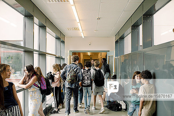 Rear view of students walking in school corridor during break