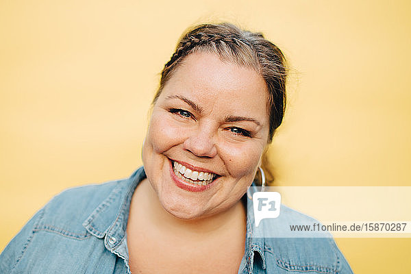 Porträt einer lächelnden reifen Frau vor gelbem Hintergrund