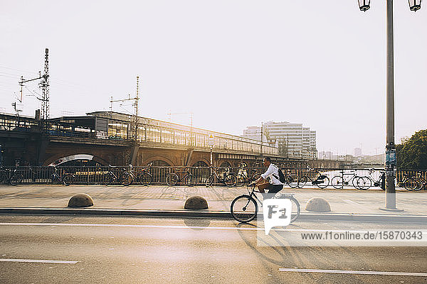 Seitenansicht einer männlichen Führungskraft auf der Straße in der Stadt mit dem Fahrrad gegen den Himmel