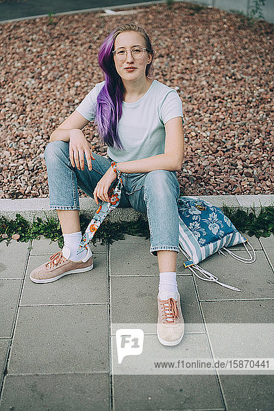 Portrait of confident teenager sitting on land