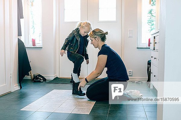 Mutter hilft Tochter mit Schuhen in Türnähe zu Hause