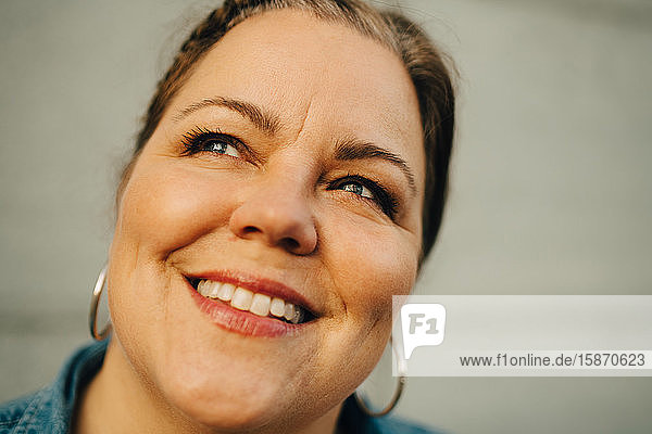 Close-up of smiling mature woman against wall