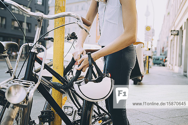 Mitten in der Stadt: Geschäftsfrau schließt Fahrrad mit Stange auf dem Bürgersteig ab