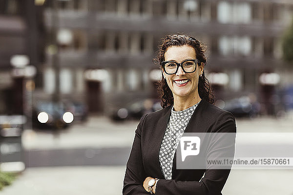 Portrait of smiling businesswoman with arms crossed standing outdoors