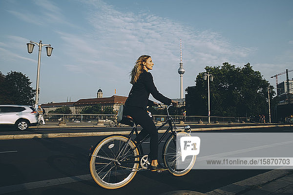 Side view of businesswoman riding bicycle on street in city
