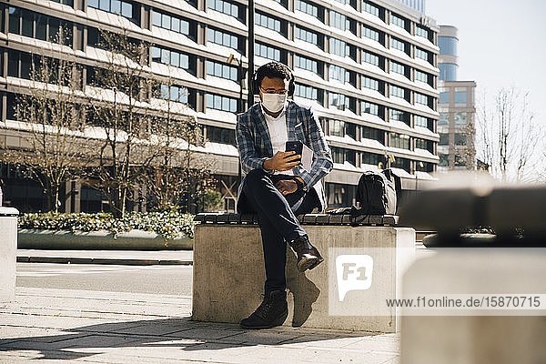 Businessman with face mask using mobile phone
