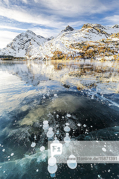 Methane bubbles in the icy surface of Silsersee with snowy peak Lake Sils Engadine Valley Graubunden Swiss Alps Switzerland Europe