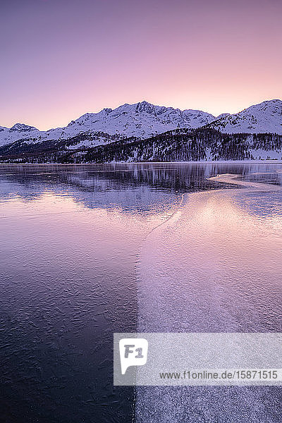 Colors of sunrise is reflected on the icy surface of Lake Sils Engadine Valley Graubunden Swiss Alps Switzerland Europe