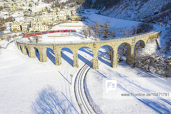 Bernina Express passes over the helical (spiral) viaduct of Brusio UNESCO World Heritage Site Valposchiavo Canton of Graubunden Switzerland Europe