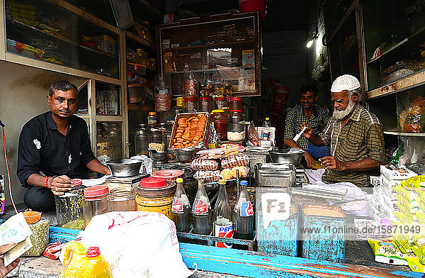 Dörfliche Gemischtwarenläden  muslimischer Ladenbesitzer misst Honig für einen Kunden ab  Dorf Dasada  Gujarat  Indien  Asien