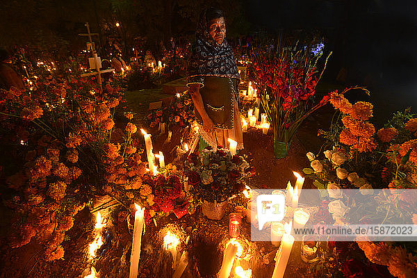Zapotekische Frau mit Kerze zwischen mit Ringelblumen geschmückten Gräbern  Atzompa  Oaxaca  Mexiko  Nordamerika