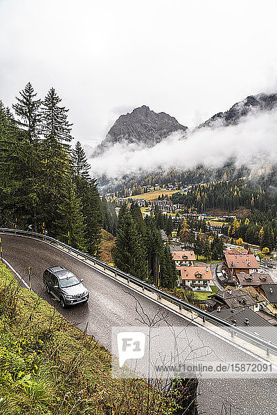 Car travelling on mountain road towards the village of Canazei in autumn Dolomites Val di Fassa Trentino-Alto Adige Italy Europe
