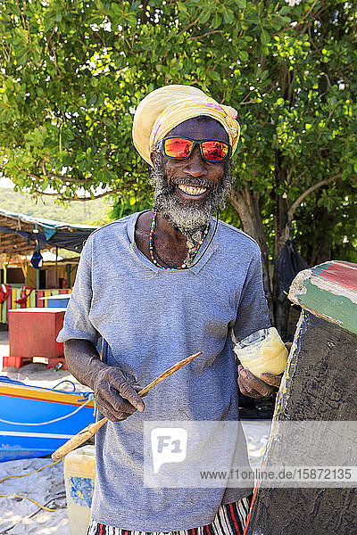 Grinsender Mann repariert Boot  farbenfrohe Saltwhistle Bay  Mayreau  Grenadinen  St. Vincent und die Grenadinen  Inseln über dem Winde  Westindische Inseln  Karibik  Mittelamerika