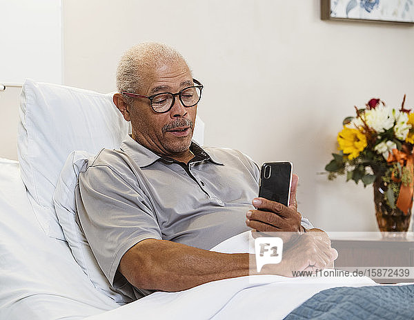 Älterer Mann benutzt Smartphone im Bett