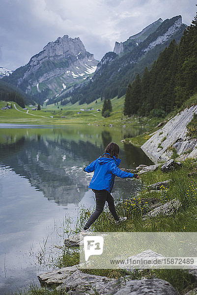 Junge Frau in blauer Jacke geht am See spazieren