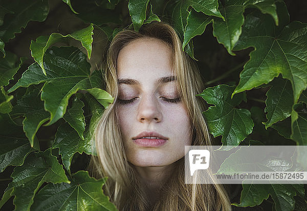 Frau mit geschlossenen Augen inmitten von Blättern